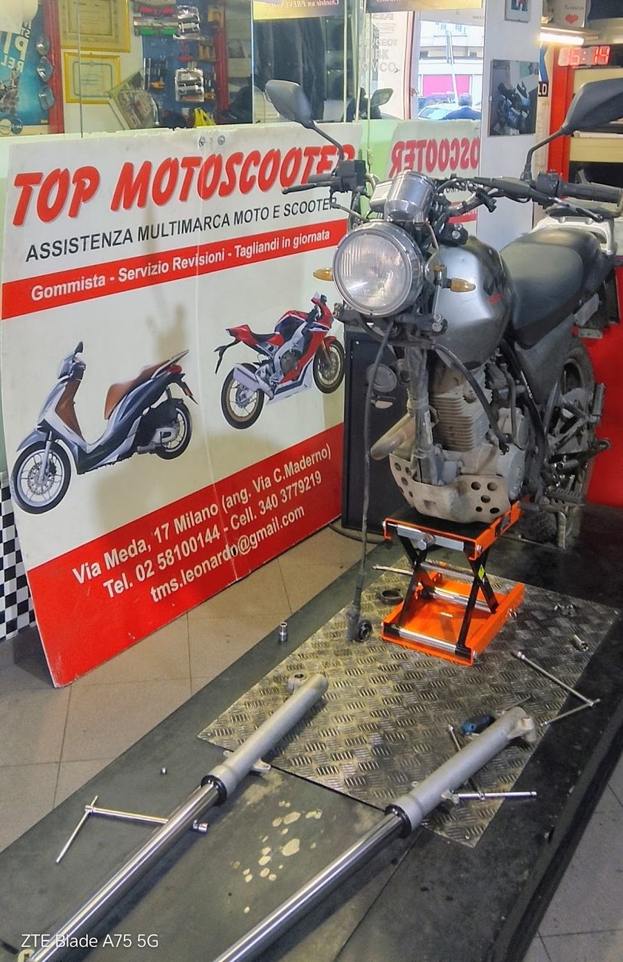 Una moto sul ponte dell'officina, con le forcelle smontate a terra